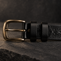 Detail of the antique-brass buckle and round rivet stud on the Midnight Black Tooled Belt.