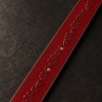 Close-up of the hand-tooled floral engraving on the Bordeaux leather strap.