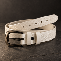 DIRATH Tooled Belt in Ivory — full-length view of the hand-tooled full-grain leather strap with antique-brass buckle.